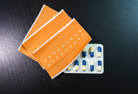 Multicolor vitamins and bend aids on black background. Concept for a healthy dietary supplementation