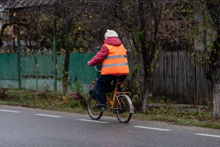 An unidentified middle aged woman riding a bicycle on a cloudy dark day. Targoviste, Romania, 2019.のeditorial素材