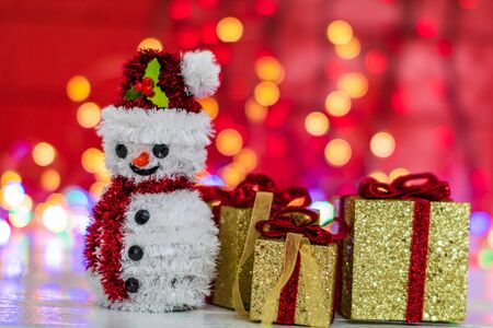 Christmas composition on blurred lights background. Snowman figurine and glittery Christmas gifts.の写真素材