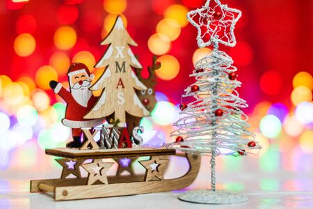 Christmas decorations against blurred background and out of focus lights. Close up of a wooden Christmas sledge with Santa Claus, a reindeer, Christmas treeの写真素材
