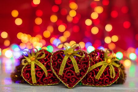 Glittery heart shaped Christmas balls. Christmas decorations on blurred lights background.の写真素材
