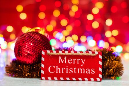 Merry Christmas wooden sign. Christmas composition on blurred lights background. Colorful Christmas balls.の写真素材
