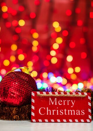 Merry Christmas wooden sign. Christmas composition on blurred lights background. Colorful Christmas balls.の写真素材