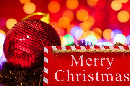 Merry Christmas wooden sign. Christmas composition on blurred lights background. Colorful Christmas balls.の写真素材