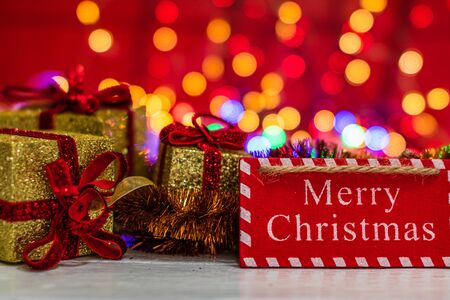 Merry Christmas wooden sign and glittery Christmas gifts. Christmas composition on blurred lights background.の写真素材
