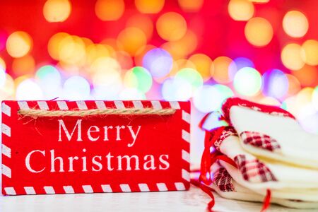 Merry Christmas wooden sign and small Christmas stockings. Christmas composition on blurred lights background.の写真素材