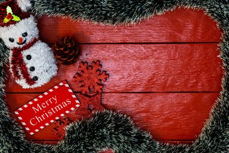 Christmas composition on red wooden board with Christmas garland and decorations. Creative composition with border and copy space, top view, flat lay. Christmas frame.の写真素材