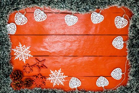 Christmas composition on red wooden board with Christmas garland and decorations. Creative composition with border and copy space, top view, flat lay. Christmas frame.の写真素材