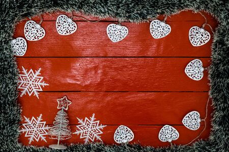 Christmas composition on red wooden board with Christmas garland and decorations. Creative composition with border and copy space, top view, flat lay. Christmas frame.の写真素材