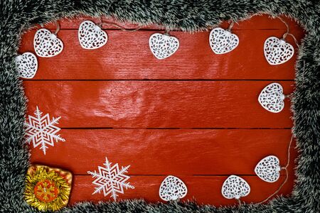 Christmas composition on red wooden board with Christmas garland and decorations. Creative composition with border and copy space, top view, flat lay. Christmas frame.の写真素材