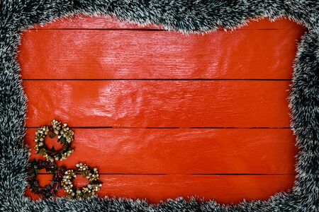 Christmas composition on red wooden board with Christmas garland and decorations. Creative composition with border and copy space, top view, flat lay. Christmas frame.の写真素材