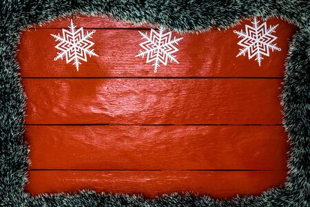 Christmas composition on red wooden board with Christmas garland and decorations. Creative composition with border and copy space, top view, flat lay. Christmas frame.の写真素材