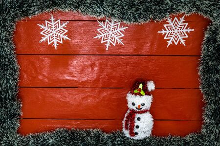 Christmas composition on red wooden board with Christmas garland and decorations. Creative composition with border and copy space, top view, flat lay. Christmas frame.の写真素材