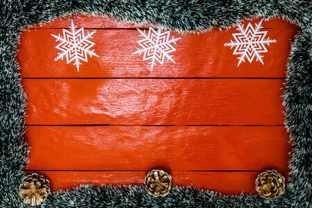 Christmas composition on red wooden board with Christmas garland and decorations. Creative composition with border and copy space, top view, flat lay. Christmas frame.の写真素材