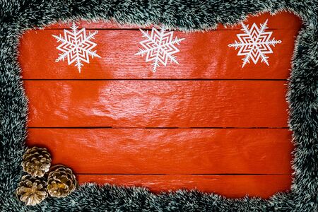 Christmas composition on red wooden board with Christmas garland and decorations. Creative composition with border and copy space, top view, flat lay. Christmas frame.の写真素材