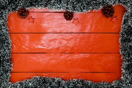 Christmas composition on red wooden board with Christmas garland and decorations. Creative composition with border and copy space, top view, flat lay. Christmas frame.の写真素材