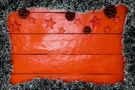 Christmas composition on red wooden board with Christmas garland and decorations. Creative composition with border and copy space, top view, flat lay. Christmas frame.の写真素材