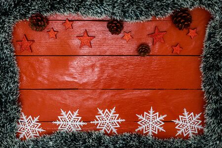 Christmas composition on red wooden board with Christmas garland and decorations. Creative composition with border and copy space, top view, flat lay. Christmas frame.の写真素材