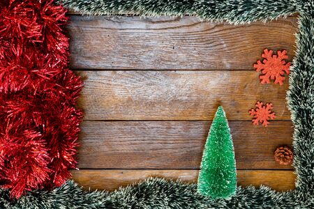 Christmas composition on wooden board with Christmas garland and decorations. Creative composition with border and copy space, top view, flat lay. Christmas frame.の写真素材