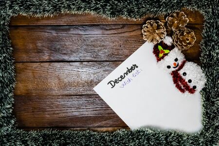 Paper with wish list for December. Christmas decorations on wooden board. Christmas concept.の写真素材