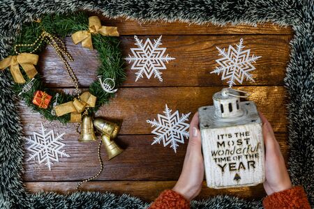 Christmas composition on wooden board with Christmas garland and decorations. Hands holding Christmas decorations.の写真素材