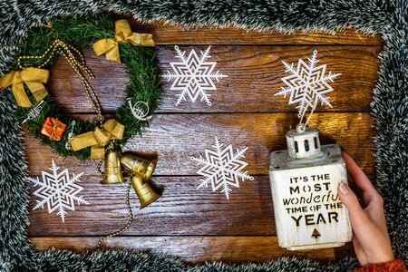 Christmas composition on wooden board with Christmas garland and decorations. Hands holding Christmas decorations.の写真素材