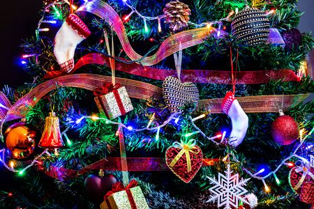 Christmas hanging decorations on fir tree. Decorated Christmas tree. Fir branch with Christmas decorations surrounded by lights and garlands.の写真素材
