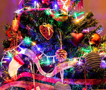 Christmas hanging decorations on fir tree. Decorated Christmas tree. Fir branch with Christmas decorations surrounded by lights and garlands.の写真素材