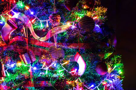 Christmas hanging decorations on fir tree. Decorated Christmas tree. Fir branch with Christmas decorations surrounded by lights and garlands.の写真素材