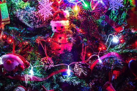 Christmas hanging decorations on fir tree. Decorated Christmas tree. Fir branch with Christmas decorations surrounded by lights and garlands.の写真素材