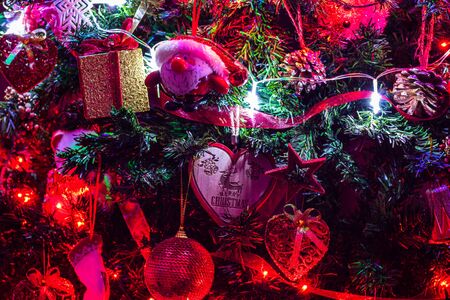 Christmas hanging decorations on fir tree. Decorated Christmas tree. Fir branch with Christmas decorations surrounded by lights and garlands.の写真素材