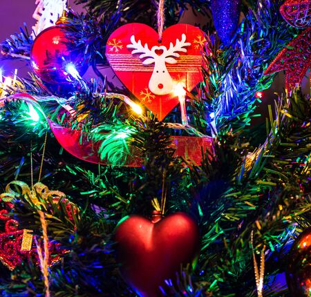Christmas hanging decorations on fir tree. Decorated Christmas tree. Fir branch with Christmas decorations surrounded by lights and garlands.の写真素材