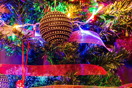 Christmas hanging decorations on fir tree. Decorated Christmas tree. Fir branch with Christmas decorations surrounded by lights and garlands.の写真素材