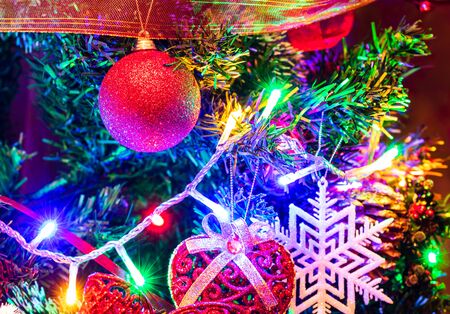 Christmas hanging decorations on fir tree. Decorated Christmas tree. Fir branch with Christmas decorations surrounded by lights and garlands.の写真素材