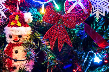 Christmas hanging decorations on fir tree. Decorated Christmas tree. Fir branch with Christmas decorations surrounded by lights and garlands.の写真素材
