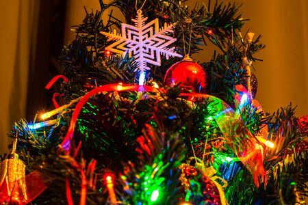 Christmas hanging decorations on fir tree. Decorated Christmas tree. Fir branch with Christmas decorations surrounded by lights and garlands.の写真素材
