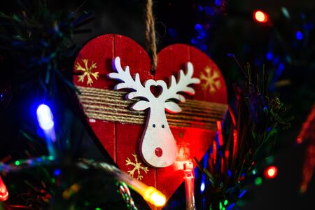 Christmas hanging decorations on fir tree. Decorated Christmas tree. Fir branch with Christmas heart shaped decoration surrounded by lights and garlands.の写真素材