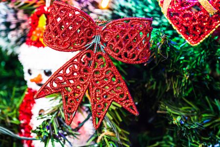 Christmas hanging decorations on fir tree. Decorated Christmas tree. Fir branch with glittery Christmas ribbon surrounded by lights and garlands.の写真素材