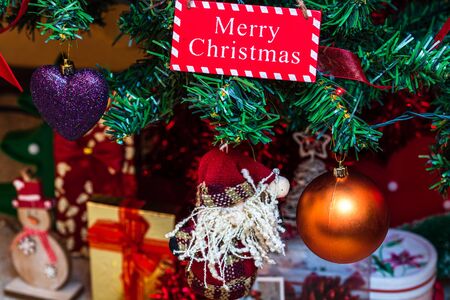 Christmas hanging decorations on fir tree. Decorated Christmas tree. Fir branch with wooden Merry Christmas sign.の写真素材