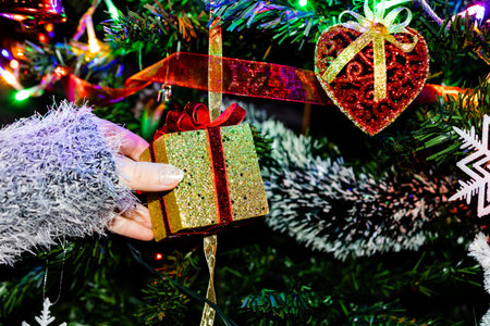 Decorating Christmas tree, hand putting Christmas decorations on fir branches. Christmas hanging decorationsの写真素材