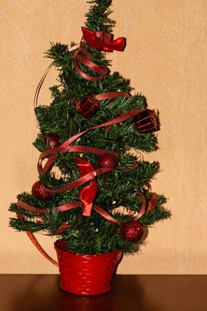 Small natural Christmas tree decorated with red decorations, baubles and garlands.の写真素材