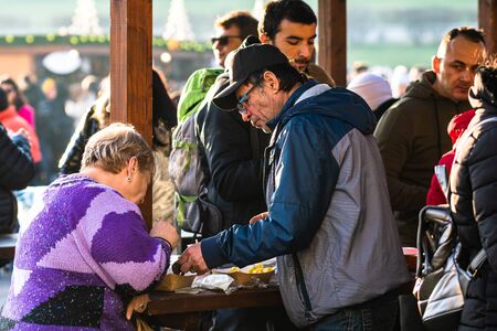 People having lunch with Romanian traditional food at Bucharest Christmas market. Bucharest, Romania, 2019.のeditorial素材