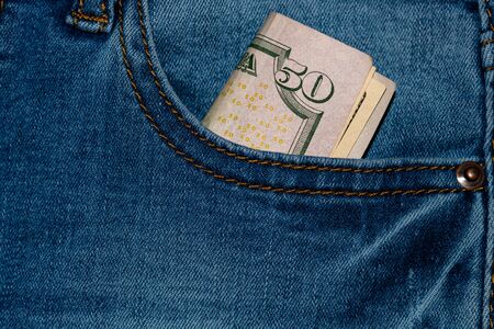 Banknotes, money in a jeans pocket, close up. Money stick out of the jeans pocket, finance and currency concept. Concept of rich people, saving or spending money.の写真素材