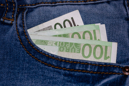 Banknotes, money in a jeans pocket, close up. Money stick out of the jeans pocket, finance and...
