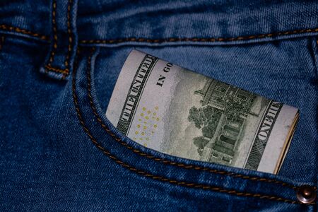 Banknotes, money in a jeans pocket, close up. Money stick out of the jeans pocket, finance and currency concept. Concept of rich people, saving or spending money.の写真素材