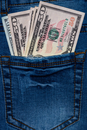Banknotes, money in a jeans pocket, close up. Money stick out of the jeans pocket, finance and...