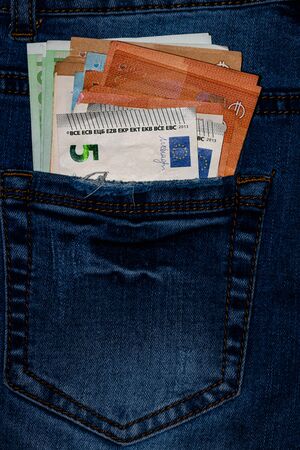 Banknotes, money in a jeans pocket, close up. Money stick out of the jeans pocket, finance and currency concept. Concept of rich people, saving or spending money.の写真素材