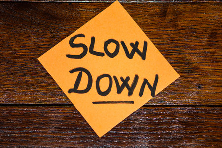 Writing on colorful sticky note slow down. Text with slow down on paper.