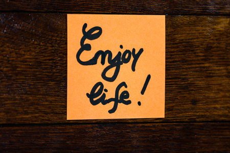 Writing on colorful sticky note Enjoy life. Text with Enjoy life on paper.