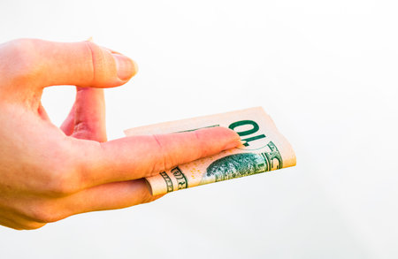 Woman hands giving money like a bribe or tips. Holding US dollars banknotes on a blurred background,...